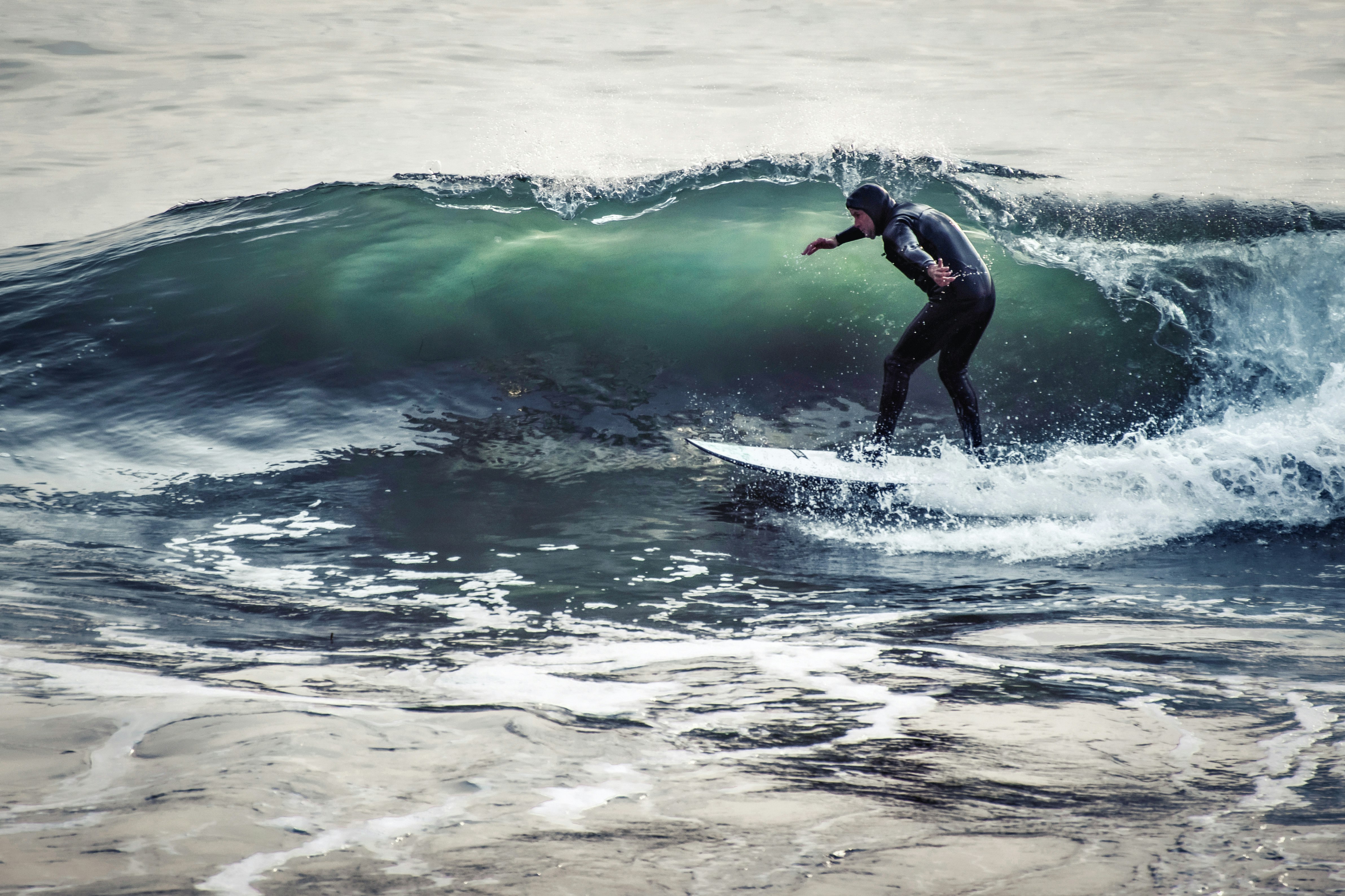 man in black wetsuit surfing on sea waves during daytime